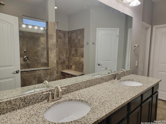 bathroom with tiled shower and vanity