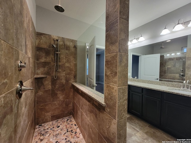 bathroom with a tile shower and vanity