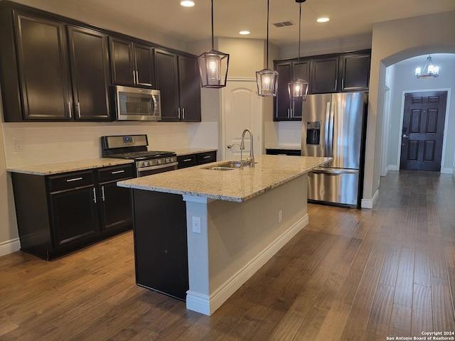 kitchen with pendant lighting, sink, light stone countertops, a center island with sink, and stainless steel appliances