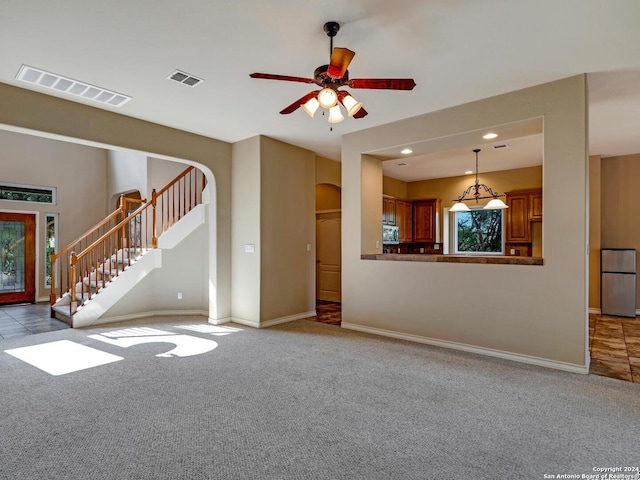 unfurnished living room featuring arched walkways, light colored carpet, visible vents, baseboards, and stairs