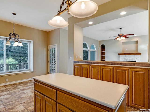 kitchen featuring ceiling fan, pendant lighting, a fireplace, and a center island