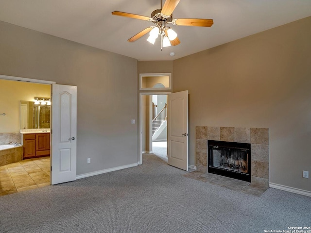 unfurnished living room with a ceiling fan, a tile fireplace, light carpet, and baseboards