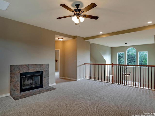 unfurnished living room with light carpet, ceiling fan, a tile fireplace, and baseboards