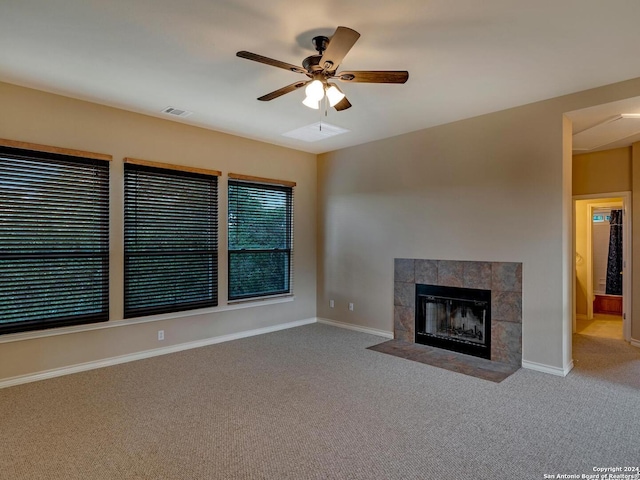 unfurnished living room with ceiling fan, carpet flooring, and a tiled fireplace