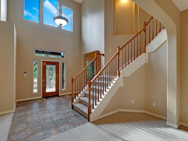 carpeted entrance foyer with a high ceiling, stairs, arched walkways, and a wealth of natural light