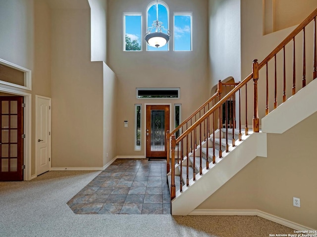 entrance foyer with carpet, a high ceiling, stairway, and baseboards