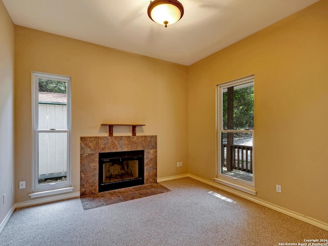 unfurnished living room featuring carpet floors, baseboards, and a tiled fireplace