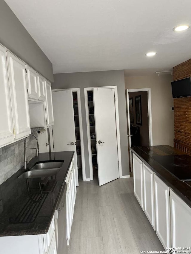 kitchen with light hardwood / wood-style flooring, white cabinets, backsplash, dishwasher, and sink