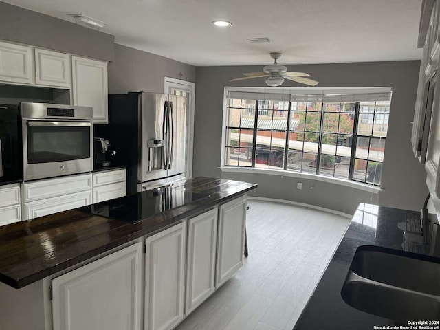 kitchen featuring white cabinetry, light wood-type flooring, ceiling fan, stainless steel appliances, and sink