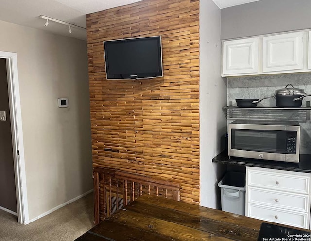 kitchen featuring rail lighting, carpet, and white cabinets