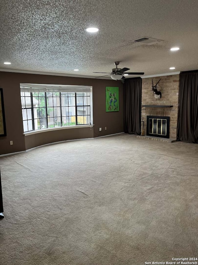 unfurnished living room with a textured ceiling, a brick fireplace, carpet flooring, brick wall, and ceiling fan