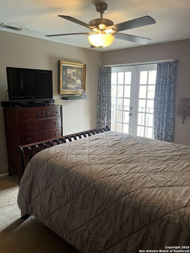 carpeted bedroom with a textured ceiling, french doors, and ceiling fan