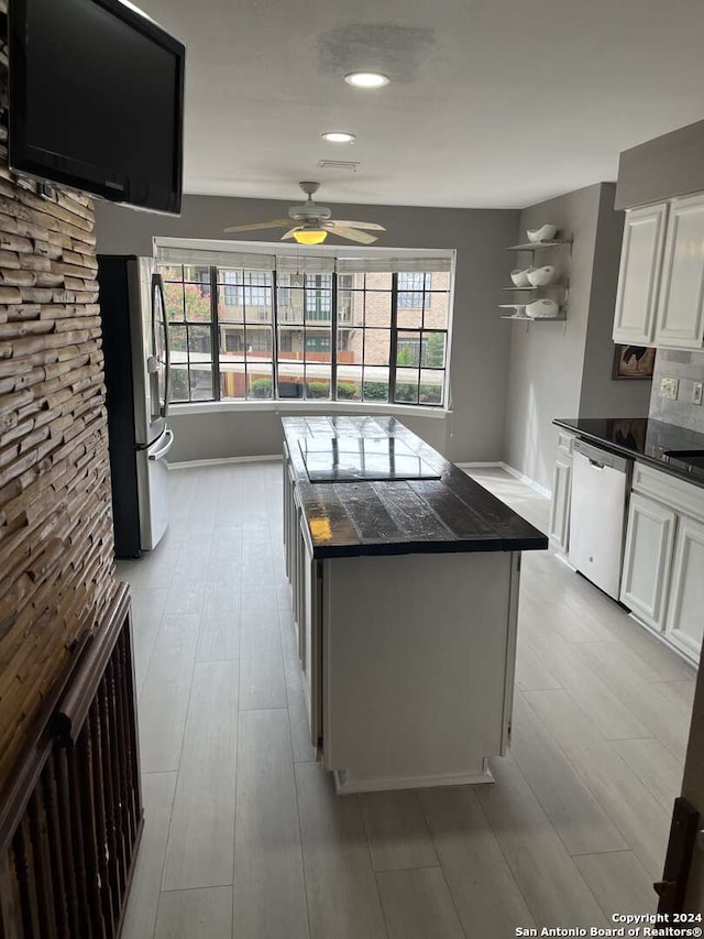 kitchen with appliances with stainless steel finishes, light wood-type flooring, ceiling fan, and white cabinetry