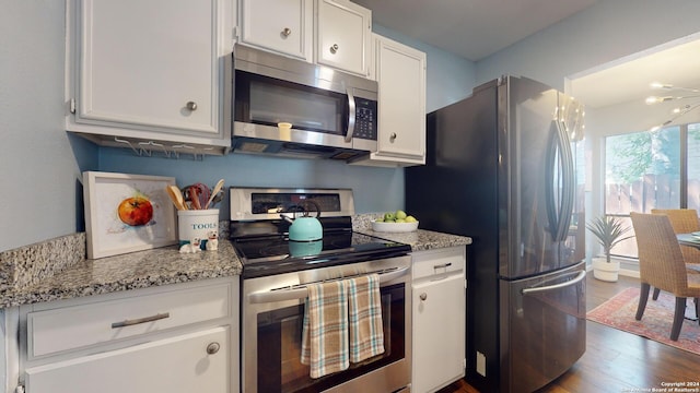 kitchen featuring light stone counters, appliances with stainless steel finishes, dark hardwood / wood-style flooring, and white cabinets