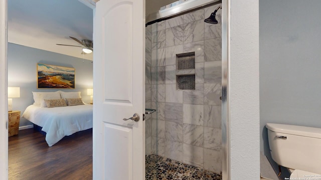 bathroom featuring hardwood / wood-style floors, a shower with door, toilet, and ceiling fan