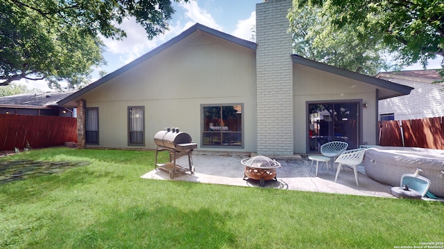 back of house featuring a yard, a patio area, and a fire pit