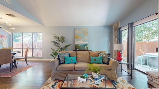 living room with an inviting chandelier, a healthy amount of sunlight, dark hardwood / wood-style floors, and vaulted ceiling