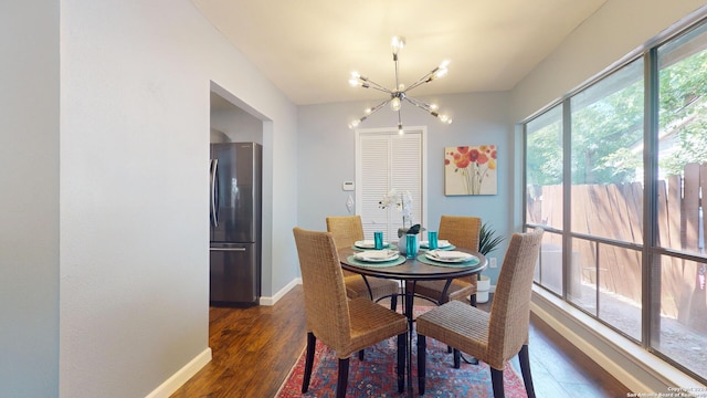 dining space featuring dark wood-type flooring and an inviting chandelier