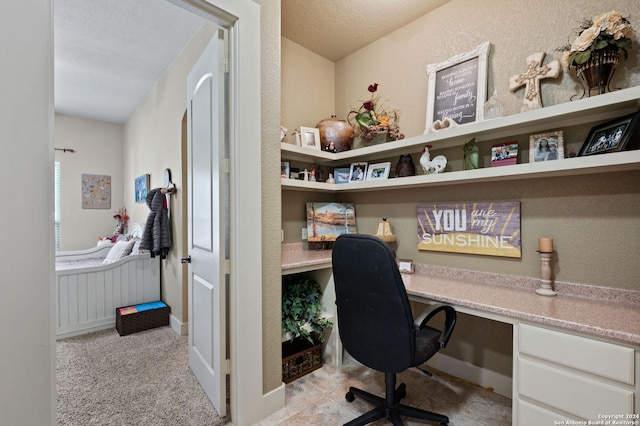 office featuring light tile patterned flooring, built in desk, and a textured ceiling