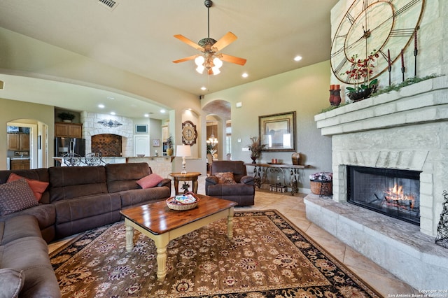 tiled living room with a stone fireplace and ceiling fan