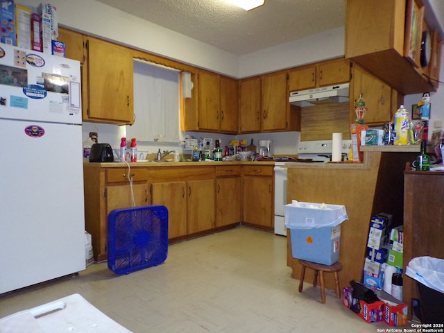 kitchen featuring sink, kitchen peninsula, white appliances, and a textured ceiling