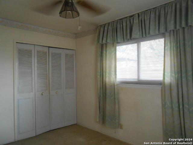 unfurnished bedroom featuring ceiling fan and a closet