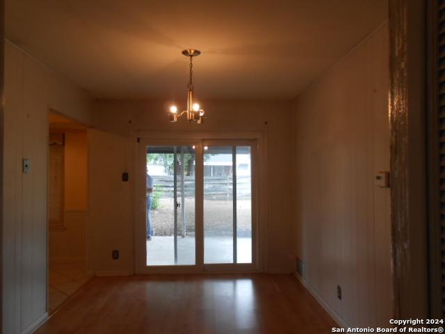 empty room featuring an inviting chandelier and hardwood / wood-style flooring