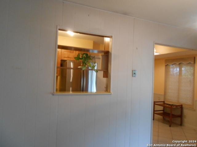 interior details featuring stainless steel refrigerator and wood walls