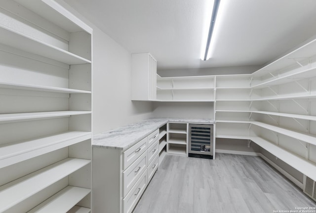 spacious closet with wine cooler and light hardwood / wood-style flooring