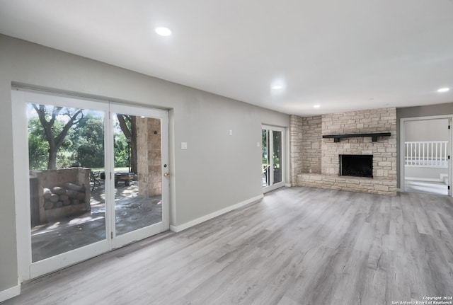 unfurnished living room featuring a stone fireplace and light hardwood / wood-style floors