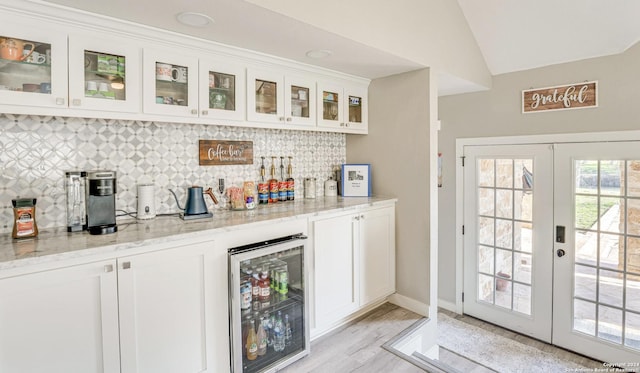 bar featuring wine cooler, vaulted ceiling, light stone counters, and white cabinets