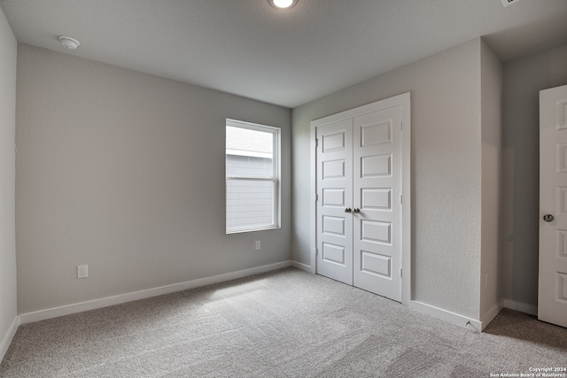 unfurnished bedroom featuring a closet and light colored carpet