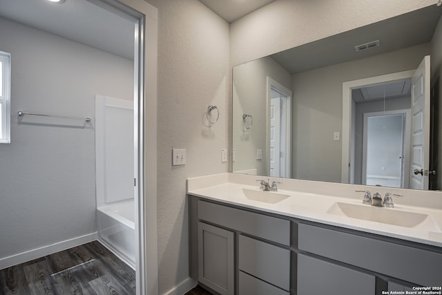 bathroom featuring hardwood / wood-style flooring, a tub to relax in, and vanity