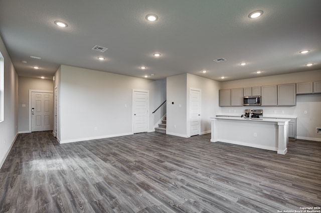 kitchen featuring dark hardwood / wood-style flooring, gray cabinetry, stainless steel appliances, and a kitchen island with sink