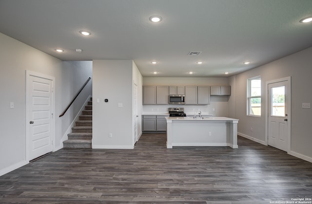 kitchen with dark hardwood / wood-style flooring, sink, gray cabinets, a center island with sink, and stainless steel appliances