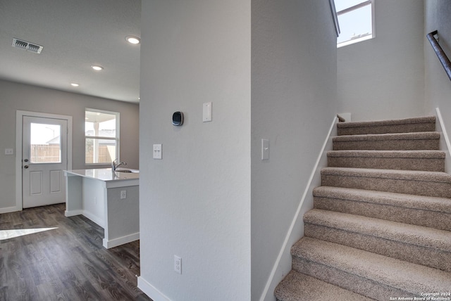 stairs with baseboards, wood finished floors, visible vents, and recessed lighting