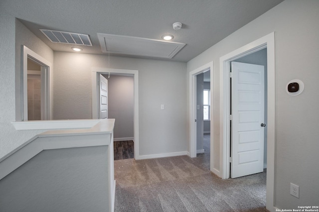 corridor with attic access, baseboards, visible vents, and carpet floors