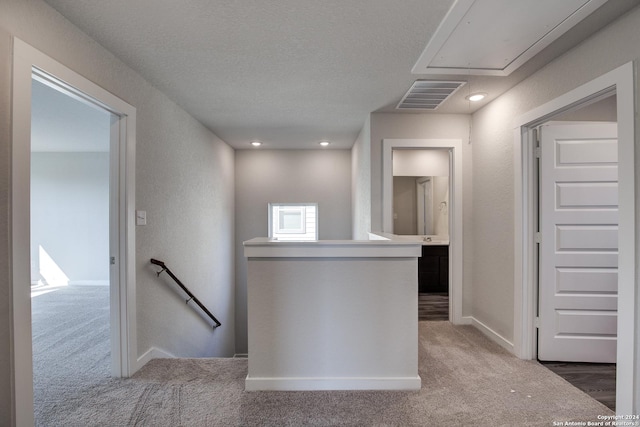hall featuring carpet, visible vents, an upstairs landing, baseboards, and attic access