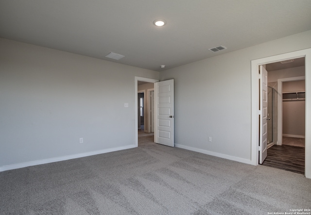 unfurnished bedroom featuring a closet, light colored carpet, and a spacious closet