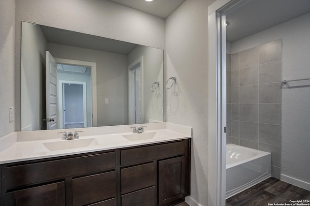 full bathroom with baseboards, wood finished floors, a sink, and double vanity