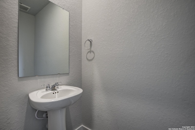 bathroom with a textured wall and visible vents