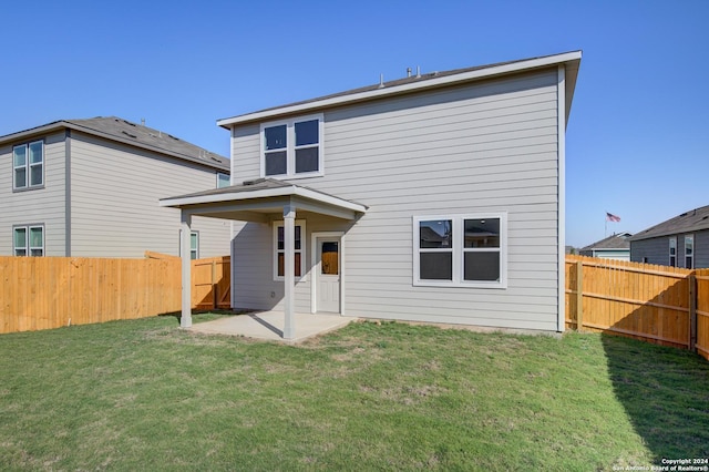 back of property with a fenced backyard, a yard, and a patio