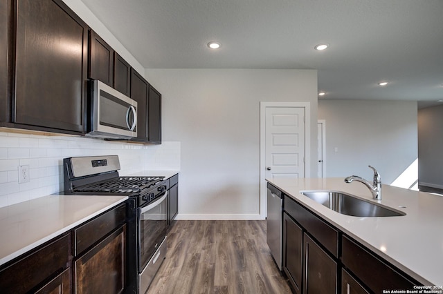 kitchen with a sink, tasteful backsplash, dark wood finished floors, light countertops, and appliances with stainless steel finishes