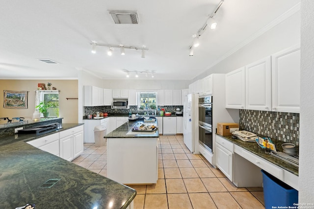 kitchen featuring a kitchen island, stainless steel appliances, white cabinets, and tasteful backsplash