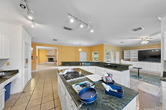 kitchen featuring white cabinets, a kitchen island, ceiling fan, and a large fireplace