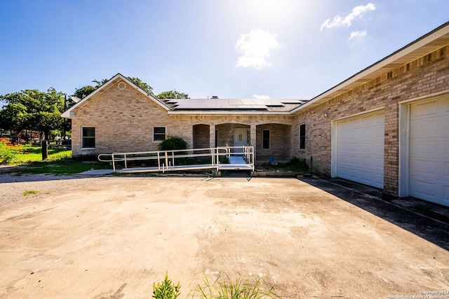 back of property with a garage and solar panels