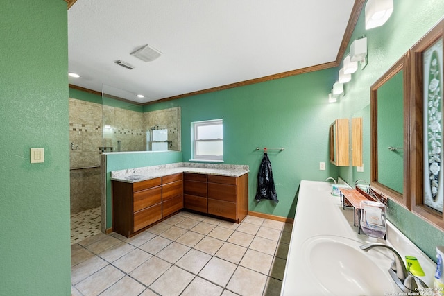 bathroom featuring tile patterned flooring, a tile shower, ornamental molding, and vanity