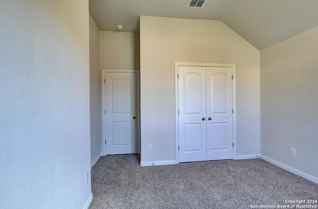 unfurnished bedroom featuring light colored carpet, a closet, and lofted ceiling