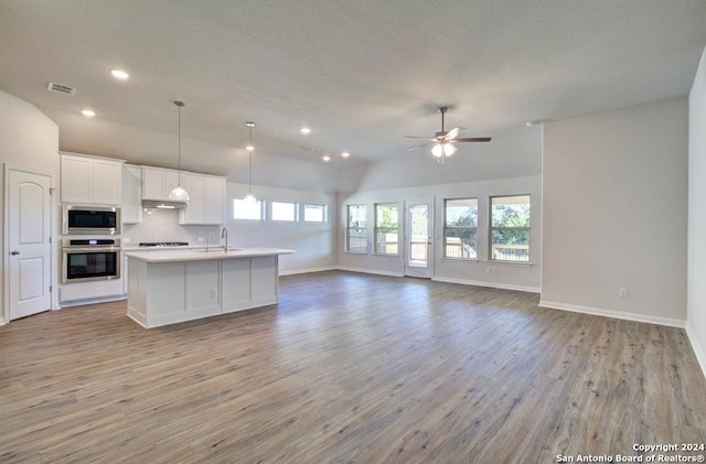 kitchen featuring tasteful backsplash, white cabinetry, hanging light fixtures, a kitchen island with sink, and stainless steel appliances