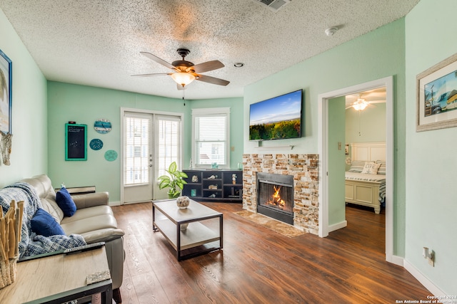 living room with a fireplace, a textured ceiling, hardwood / wood-style floors, and ceiling fan